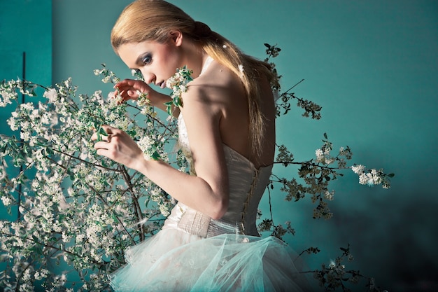 Portrait of a woman in wedding dress behind the branches with flowers