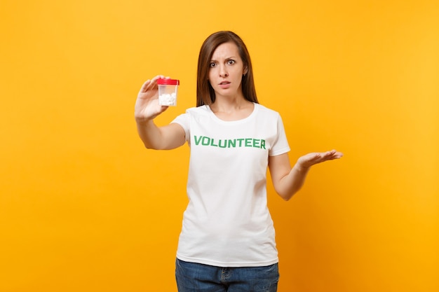 Photo portrait of woman in white t-shirt written inscription green title volunteer holding bottle with pills drug isolated on yellow background. voluntary free assistance help, charity grace health concept.