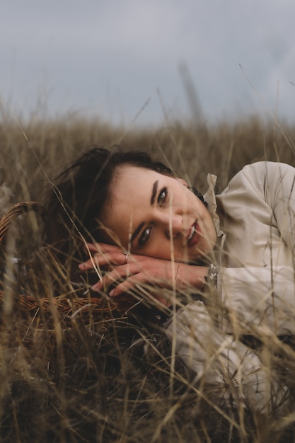 Portrait of a woman who emits suffering, calm and depression, on a field with dry grass during people