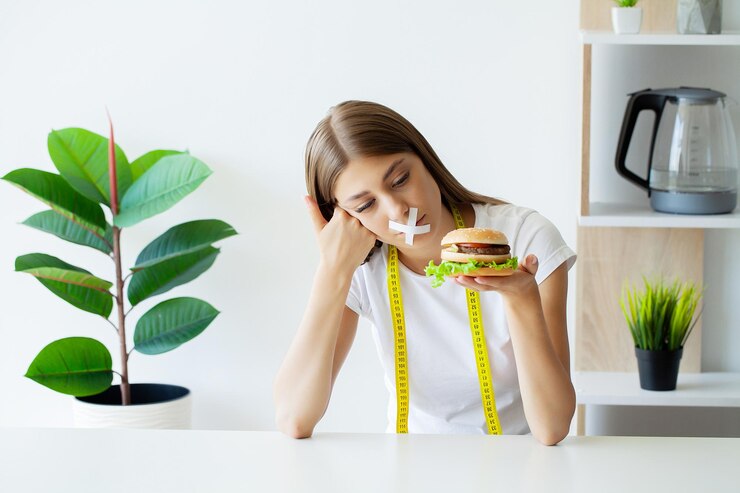 Portrait of a woman who wants to eat a burger but her mouth is taped