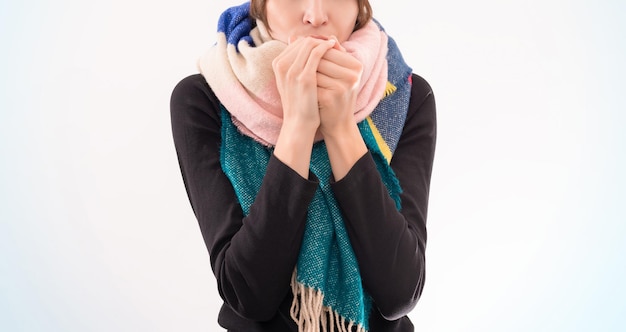 Foto ritratto di una donna con un cappello e una sciarpa invernali. si scalda le mani con il respiro. concetto di malattie virali. tecnica mista