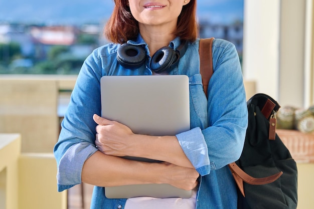 Портрет женщины в беспроводных наушниках с ноутбуком и рюкзаком