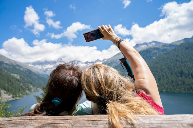 Portrait of woman with arms outstretched sitting on mountain against sky