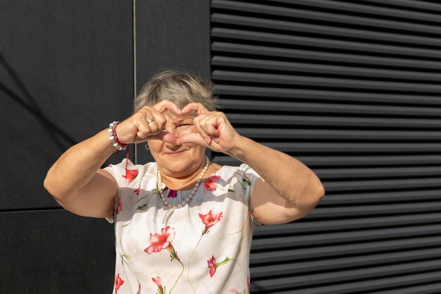 Foto ritratto di una donna con le braccia alzate in piedi contro il muro