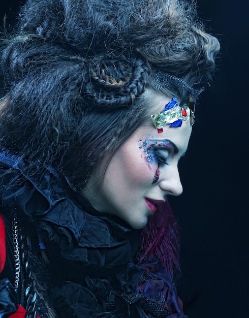 Photo portrait of woman with artistic make-up in blue smoke, party theme