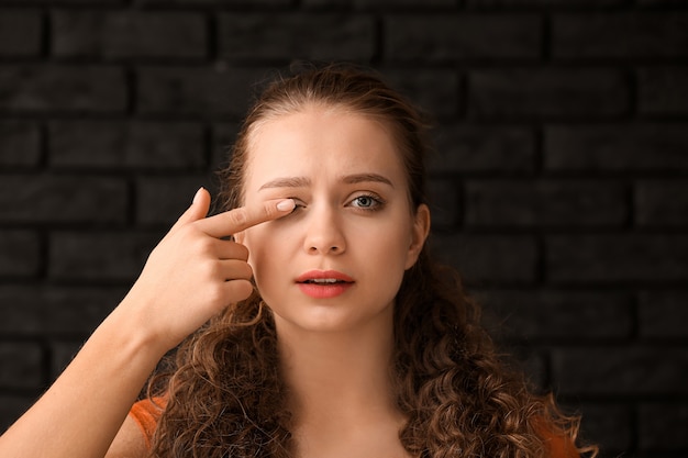 Portrait of woman with bad sight on dark brick