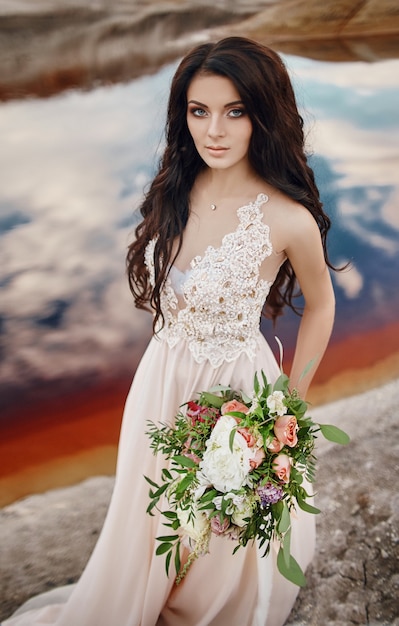 Portrait woman with blue eyes and bouquet of flowers in her hands on nature. Gorgeous hair and perfect skin, beautiful natural makeup. Girl with a bouquet of roses, mysterious dream image woman
