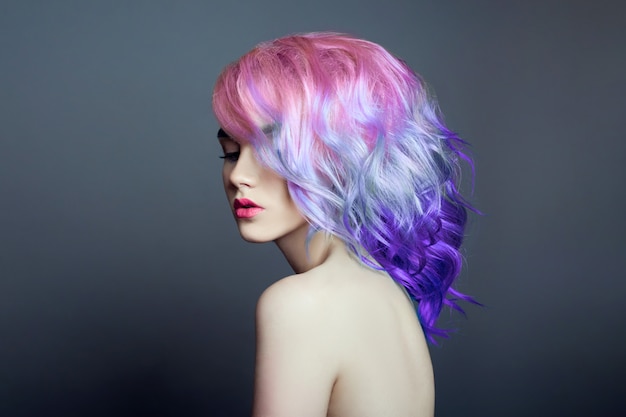 Portrait of a woman with bright colored flying hair, all shades of purple. Hair coloring, beautiful lips and makeup. Hair fluttering in the wind. Sexy girl with short  hair. Professional coloring