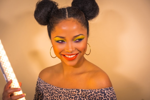 Portrait of a woman with bright makeup and two side bun hairstyle doing a claw gesture