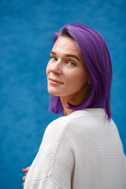 白いカーディガンの明るい紫色の髪の女性の肖像画は、彼女の左を回します。