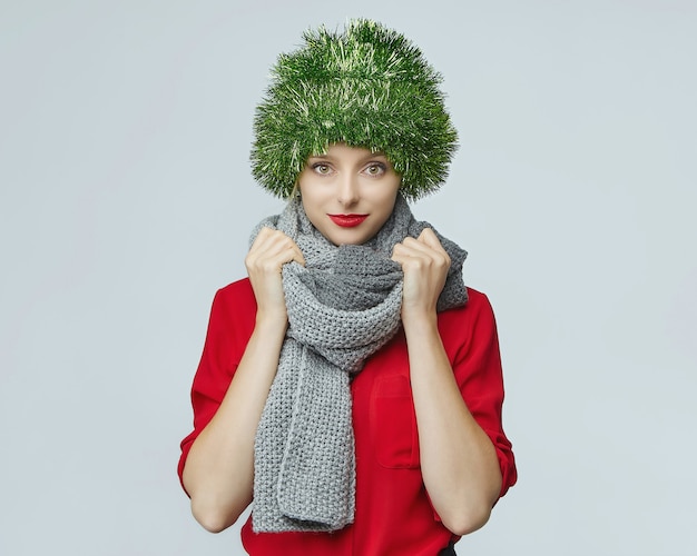 Portrait of woman with a Christmas decoration on her head on grey