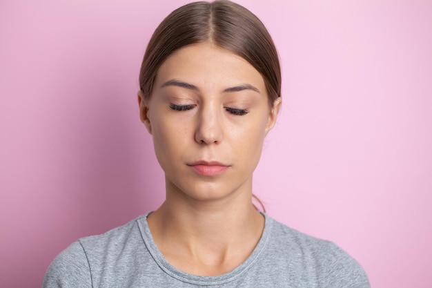 Foto ritratto di una donna con gli occhi chiusi su sfondo rosa