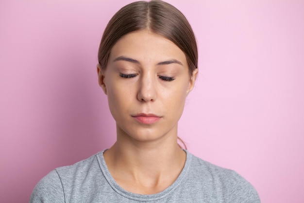 闭着眼睛的女人肖像照片在一个粉红色的背景