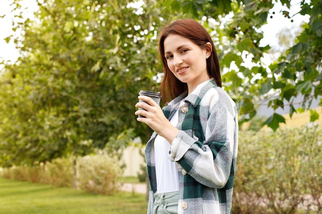 Portrait of a woman with coffee in the park on a walk in autumn