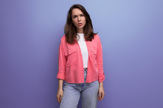 Portrait of a woman with dark brown hair in jeans and a tank top with a shirt posing in the studio