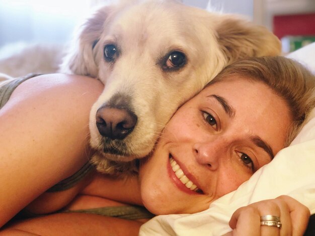 Photo portrait of woman with dog on bed