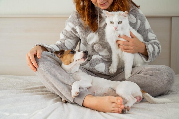 Photo portrait of woman with dog sitting on bed at home