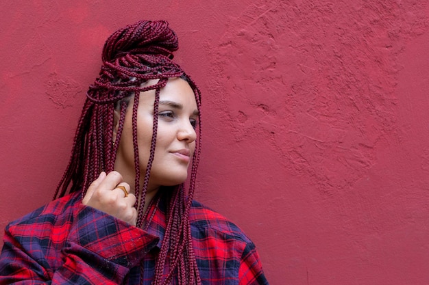 Foto ritratto di una donna con i dreadlocks sulla parete rossa