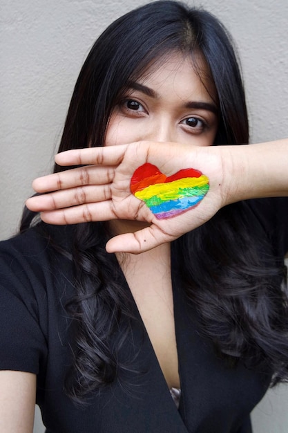 Foto ritratto di una donna con un cuore disegnato sul palmo