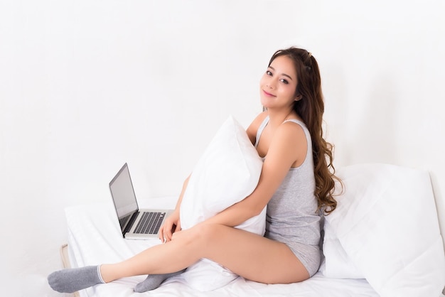 Photo portrait of woman with laptop sitting on bed at home