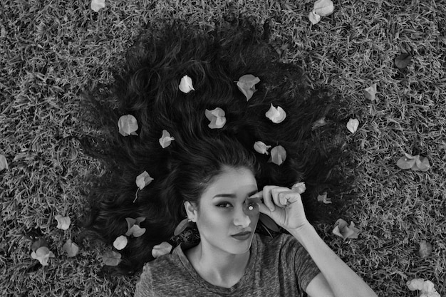 Photo portrait of woman with leaves on hair lying down at grassy field