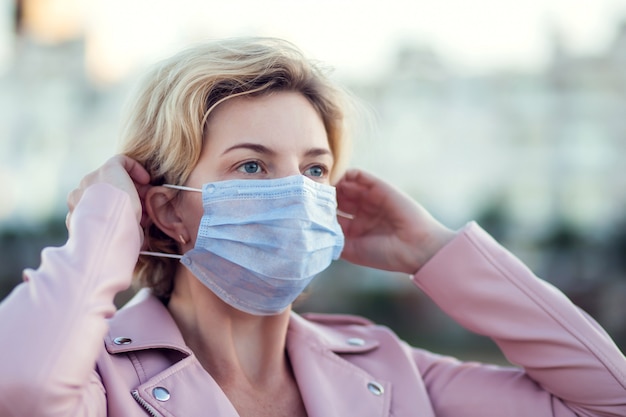 A portrait of woman with medical face mask outdoor. People, healthcare and medicine concept