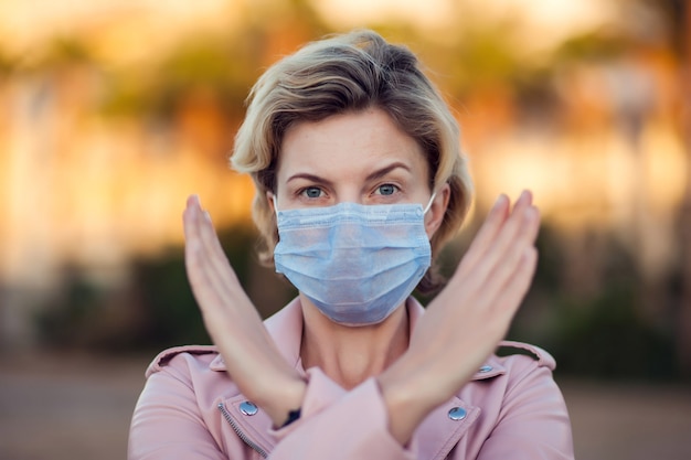 의료 얼굴 마스크 손으로 야외 정지 신호를 보여주는 여자의 초상화. 사람, 건강 관리 및 의학 개념