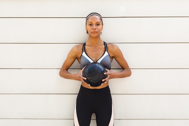 Photo portrait of woman with medicine ball standing against wall