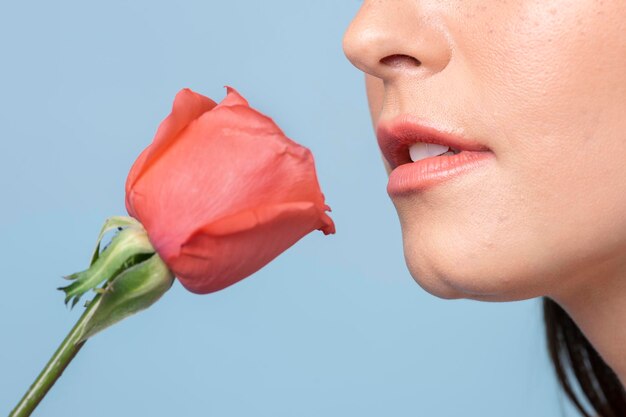 Portrait of a woman with an orange rose on blue background