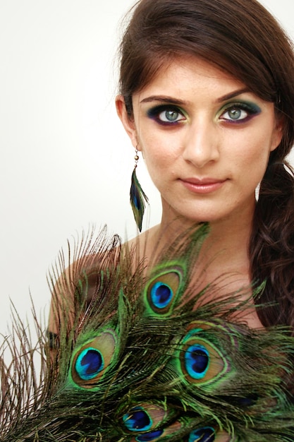 Photo portrait of woman with peacock feathers against white background