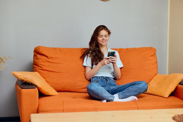 Photo portrait of a woman with a phone in his hands on the couch technologies high quality photo