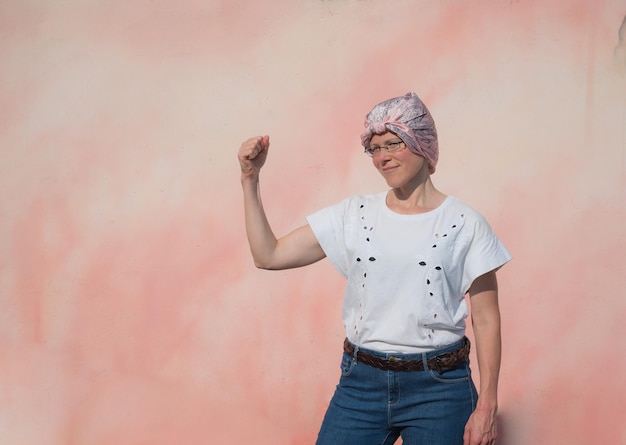 Foto ritratto di donna con sciarpa rosa ha il cancro mostra il braccio come segnale di forza