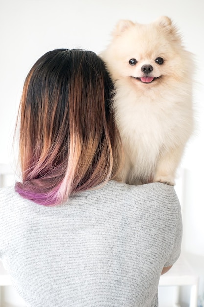 Portrait of woman with pomeranian dog at home