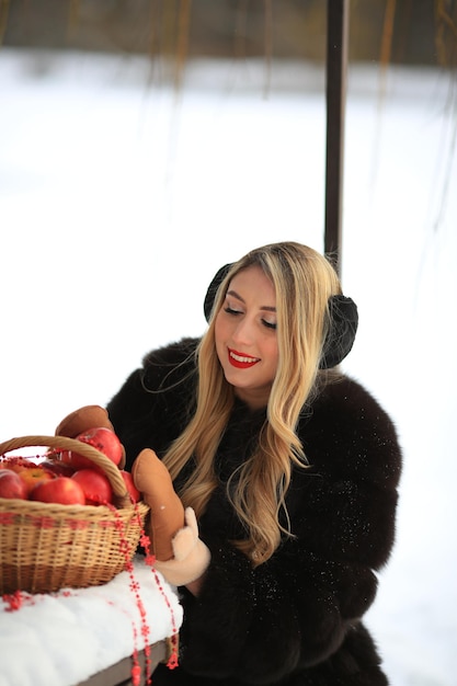 Portrait of woman with samovars bagels apples wearing traditional Slavic scarf sitting in winter