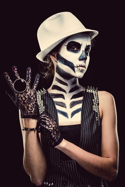 Photo portrait of woman with skull face paint wearing glove against black background