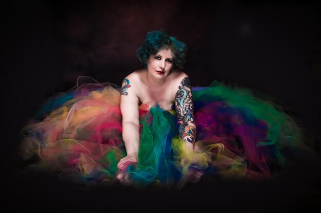 Photo portrait of woman with tattoo amidst tulle netting against black background