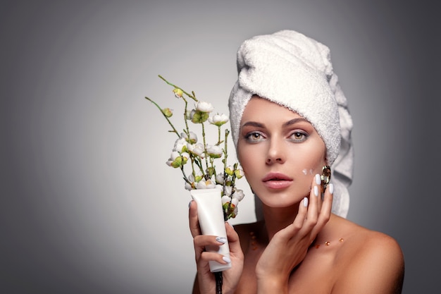 portrait woman with towel on head applying cream