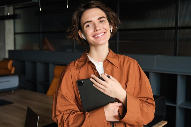 Portrait of woman working in sales marketing manager with tablet standing in office wearing casual