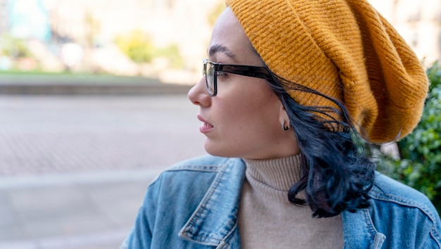 Portrait of woman in yellow hat and denim coat drinking coffee in the cafe