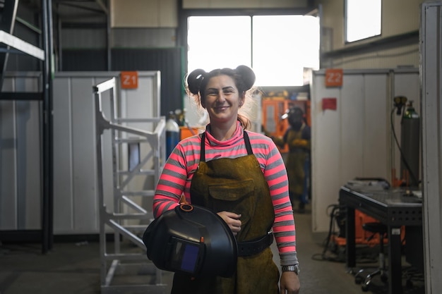 портрет женщины-сварщика, держащей каску и готовящейся к рабочему дню в металлургической промышленности. Фото высокого качества