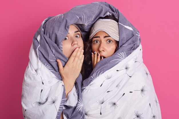 Portrait of women with blanket, posing with open mouths, keep hands near lips