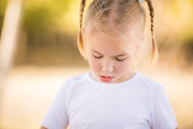 2つのお下げと疑問に思っているブロンドの女の子の肖像画