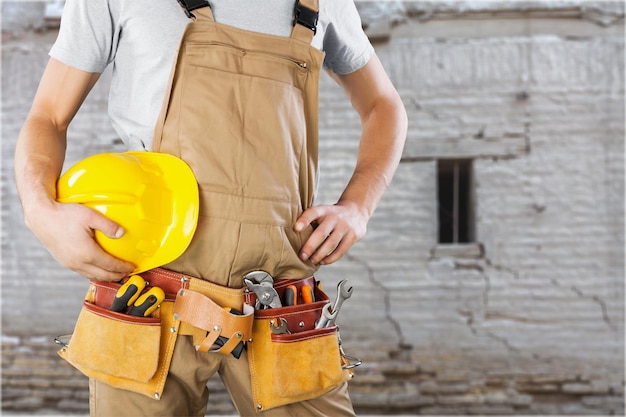 Portrait of worker man with helmet on construction side background