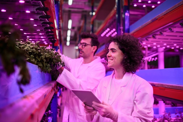 Portrait of workers using tablet on aquaponic farm, sustainable business and artificial lighting.