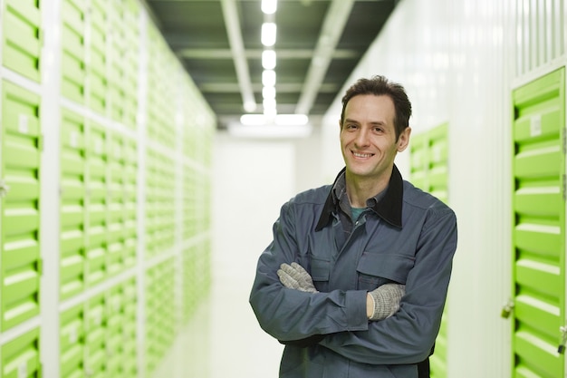 Portrait of working standing with arms crossed and smiling at camera standing in storage
