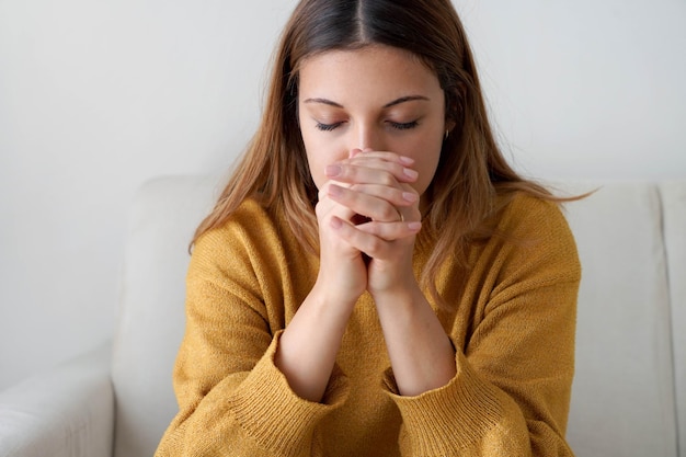 Portrait of worried woman praying at home