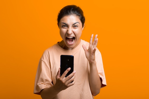 Portrait of yelling indian woman with mobile phone. Scream and social networking cleanliness tired hard work.