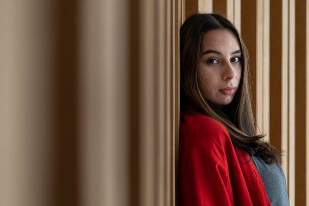 Portrait of young 23 Latin American woman looking at the camera with relaxed attitude Wooden background She is wearing a red sweater Portrait concept