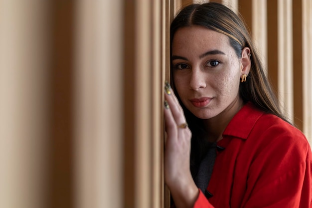 Portrait of young 23 Latin American woman looking at the camera with relaxed attitude Wooden background She is wearing a red sweater Portrait concept