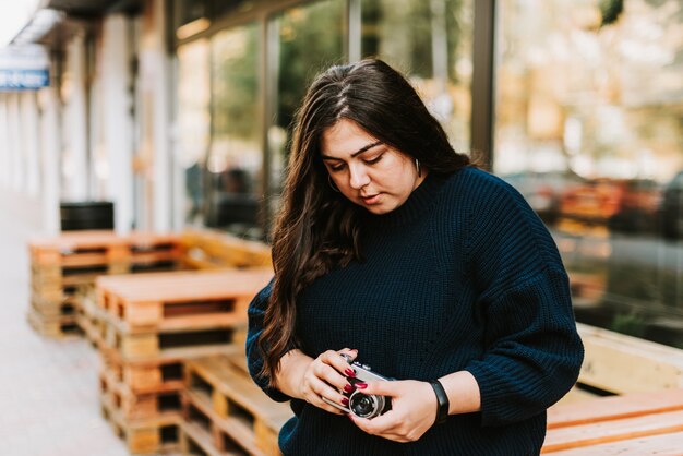 Portrait of young adult girl holding vintage camera outdoors